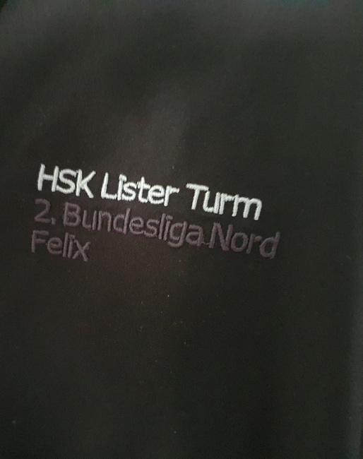 Ein Auschnitt eines schwarzen Hemds mit dem Text "HSK Lister Turm 2. Bundesliga Nord"